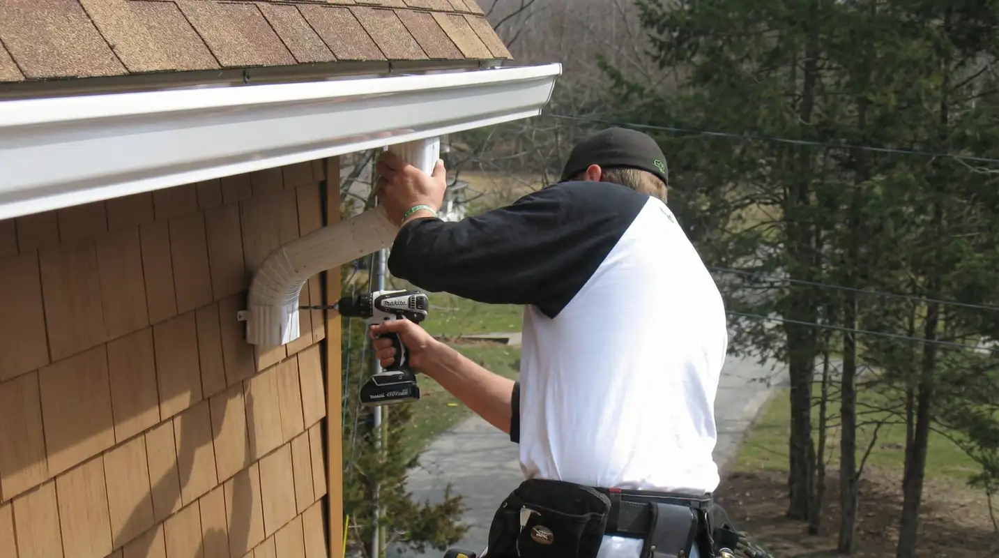 Professional contractor installing tan vinyl siding panels on a residential home exterior in New Haven, CT